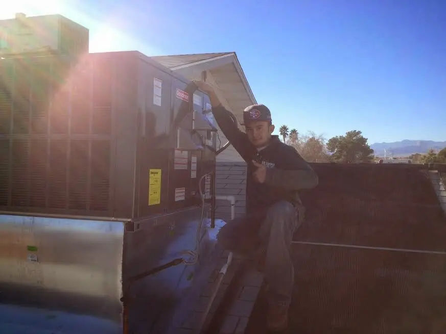 HVAC technician performing AC Tune-Up on a rooftop unit in Homeland